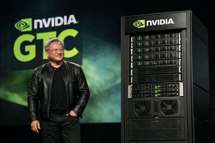 Jensen Huang on stage at Nvidia GTC beside a rack-scale AI server system during the company’s 2026 infrastructure announcements.